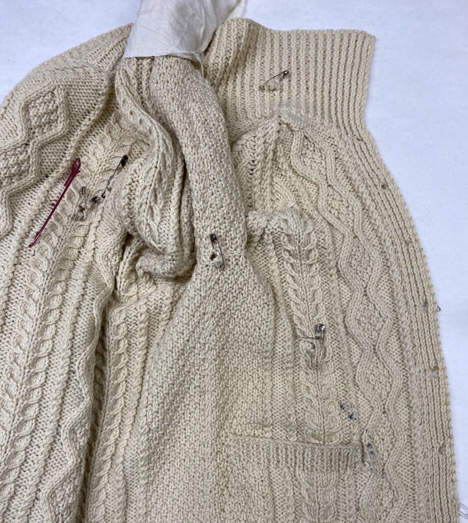 The right front side of the damaged sweater showing multiple areas needing repair