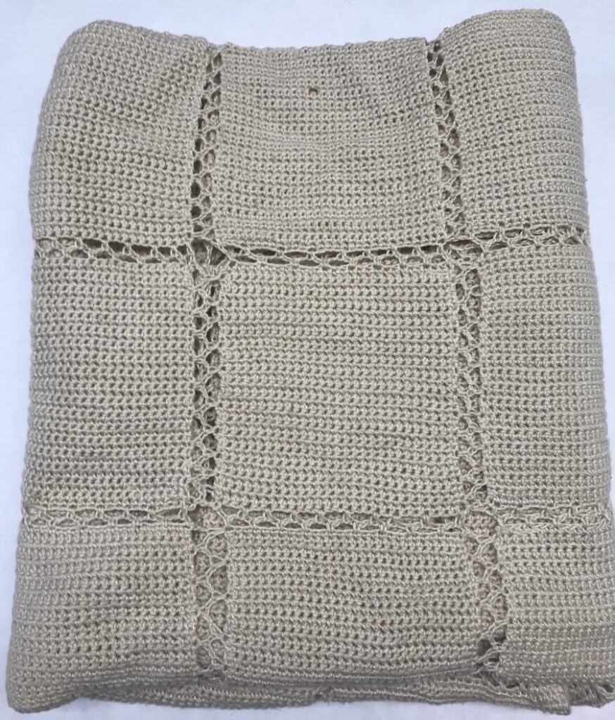 folded crocheted oatmeal colored afghan blanket